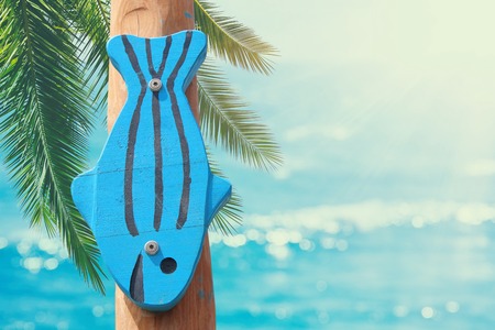 vacation and summer image with wooden decorative fish in front of the sea landscape