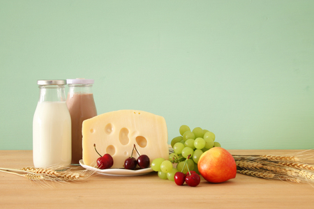 image of fruits and cheese in decorative basket with flowers over wooden table. Symbols of jewish holiday - Shavuotの写真素材