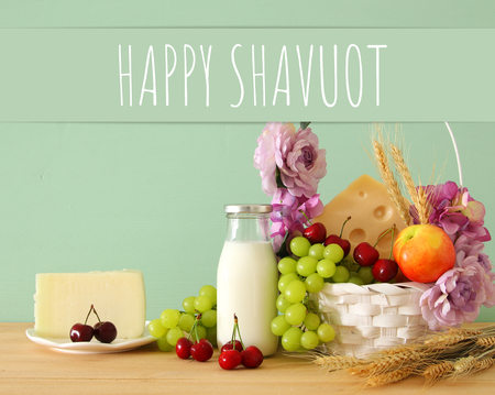 image of fruits and cheese in decorative basket with flowers over wooden table. Symbols of jewish holiday - Shavuotの写真素材