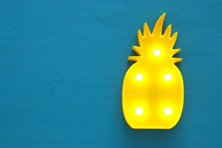 a plastic pineapple lamp with leds over blue wooden background. holiday summer conceptの写真素材