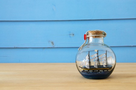 nautical concept image with sail boat in the bottle over wooden table. Selective focusの写真素材