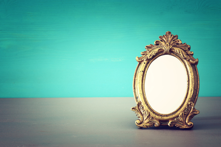 Vintage blank gold photo frame over wooden table. Ready for photography montageの写真素材