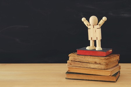 image of a wooden figure standing on a stack of books. Concept of success, education and back to school.の写真素材