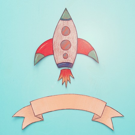 Rocket cut from paper and painted over wooden blue backgroundの写真素材