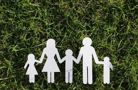 image of happy family concept. paper cut people holding hands together over green grassの写真素材
