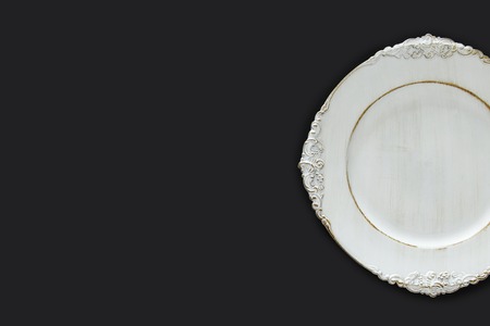 Top view of vintage white empty plate over black background. Flat layの写真素材
