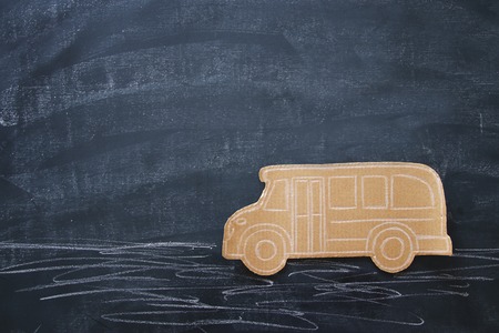 Back to school concept. Top view image cardboard school bus over classroom blackboard backgroundの写真素材