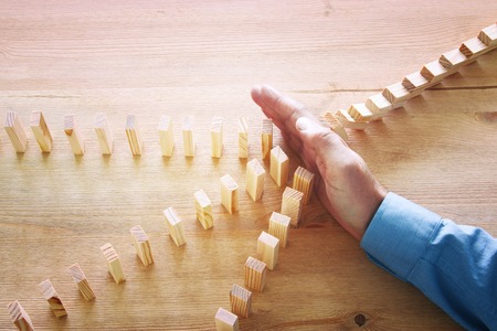 image of male hand stopping the domino effect. retro style image executive and risk control conceptの写真素材
