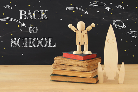 wooden rocket and space sketches with wooden dummy in front of classroom blackboardの写真素材