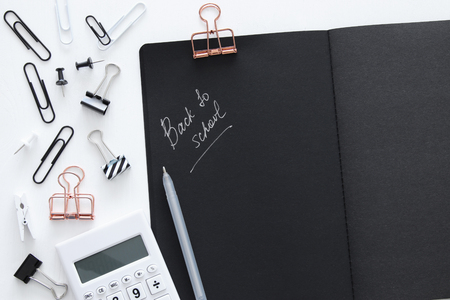 White office desk table with calculator, open notebook with black pages and other office supplies. Top viewの写真素材