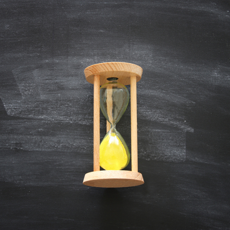Top view of hourglass over chalkboard background