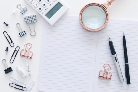 White office desk table with open notebook with empty pages and other office supplies. Top viewの写真素材