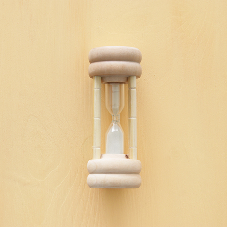 Top view of hourglass over wooden background