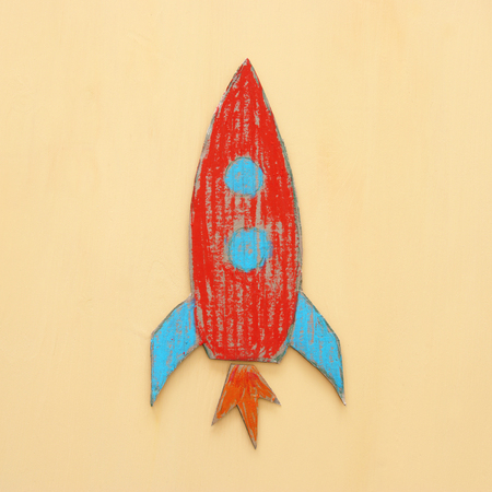 Rocket cut from cardboard and painted over wooden yellow backgroundの写真素材