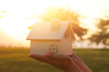 Image of woman holding small wooden house outdoors at sunset lightの写真素材