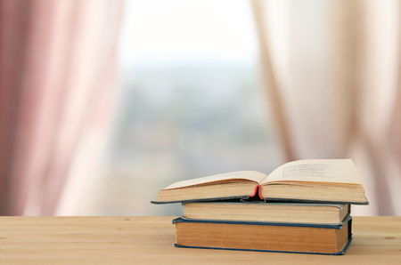 back to school concept. stack of books over wooden desk in front of day light windowの写真素材