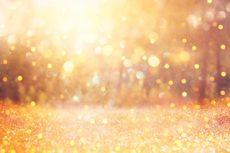 blurred abstract photo of light burst among trees and glitter golden bokeh lightsの写真素材