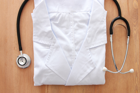 Image of stethoscope and doctor coat over wooden desk. Medical conceptの写真素材