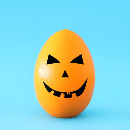minimal and funny Halloween holiday concept. Orange egg with scary cute faceの写真素材