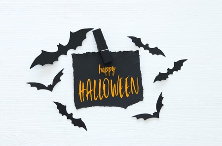 Halloween holiday minimal top view image of letter with text HAPPY HALLOWEEN over wooden white background. Card and invitation concept