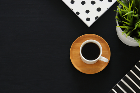 Image of coffee cup and notebook over black background. Top viewの写真素材