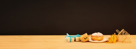 banner of jewish holiday Hanukkah with traditional doughnut and spinning top on the tableの写真素材