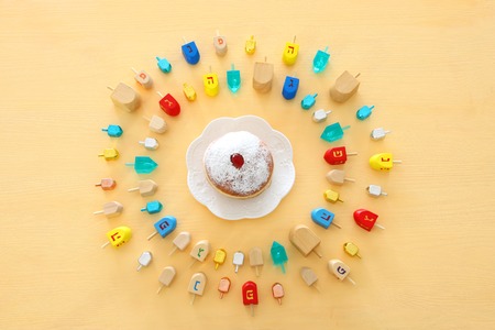 Image of jewish holiday Hanukkah with wooden dreidels colection (spinning top) and doughnut over...