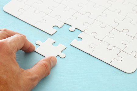 male hand putting the last piece in the puzzle