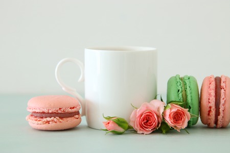 White vintage cup of coffee and colorful macaron or macaroon over pastel wooden tableの写真素材