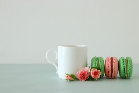 White vintage cup of coffee and colorful macaron or macaroon over pastel wooden tableの写真素材