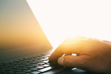 Image of man's hand typing over laptop keyboard at office, workplace or home. Vintage filteredの写真素材