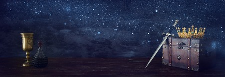 Low key banner of beautiful queen/king crown, wine cup and sword. Fantasy medieval periodの写真素材