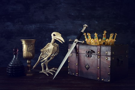 Low key image of beautiful queen/king crown, wine cup, bird skeleton and sword. Fantasy medieval periodの写真素材