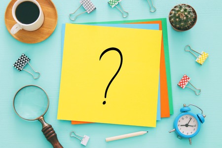Question mark over yellow paper on office table. Searching for solution. confusion concept