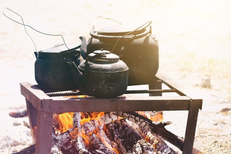 Cooking food in a rustic old kettle on bonfire in the forestの写真素材