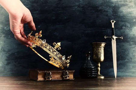 low key photo of king holding gold crown and sword. fantasy medieval periodの写真素材