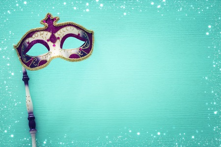 Carnival party celebration concept with elegant purple mask on stick over mint wooden background. Top viewの写真素材