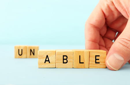 man hand spelling the text unable with wooden cubes, taking out the word un so it written able. success and challenge conceptの写真素材