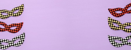 carnival party celebration concept with colorful masks over purple wooden background. Top view