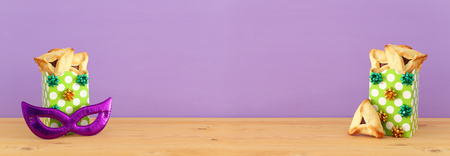 Purim celebration concept (jewish carnival holiday). Traditional hamantaschen cookies over wooden table and purple backgroundの写真素材