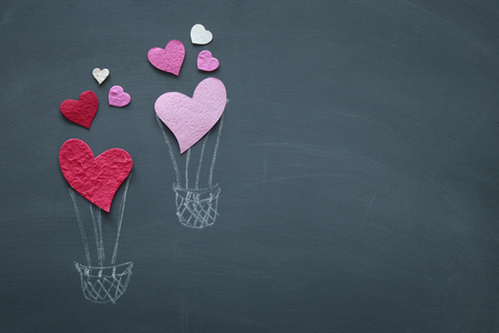 Valentine's day concept. pink and red paper hearts as air balloon over blackboardの写真素材