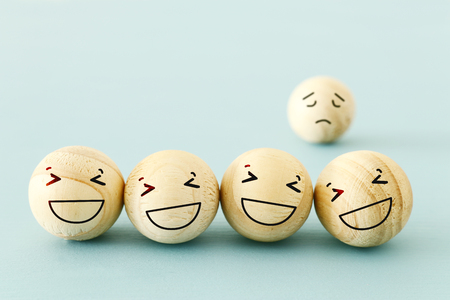 concept of bullying , discrimination. group of laughing emoticon faces and one alone look sad and depressed.の写真素材
