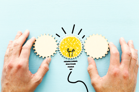 Concept photo of revealing an idea, finding the right solution during creative process. cogeheel with bright light bulbの写真素材