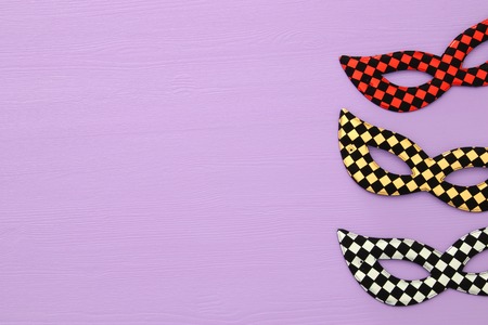 Carnival party celebration concept with colorful masks over purple wooden background. Top view. Flat...