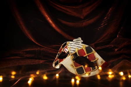 Photo of elegant and delicate Venetian mask over dark velvet and silk backgroundの写真素材