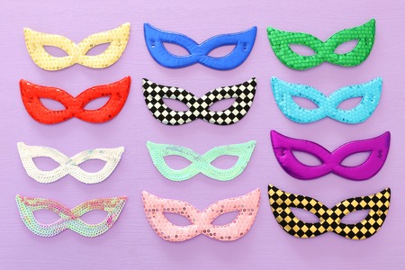 Carnival party celebration concept with collection of colorful masks over purple wooden background....