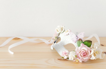 carnival party celebration concept with elegant white mask over wooden tableの写真素材
