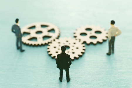 Miniature people looking at cogwheel in set of gears mechanism. Problem solving conceptの写真素材
