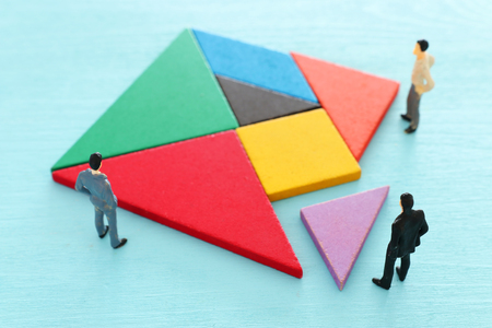 tangram puzzle blocks with miniature people over wooden table ,human resources, problem solving and...