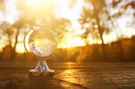 small crystal globe in front of sunset. travel and global issues conceptの写真素材